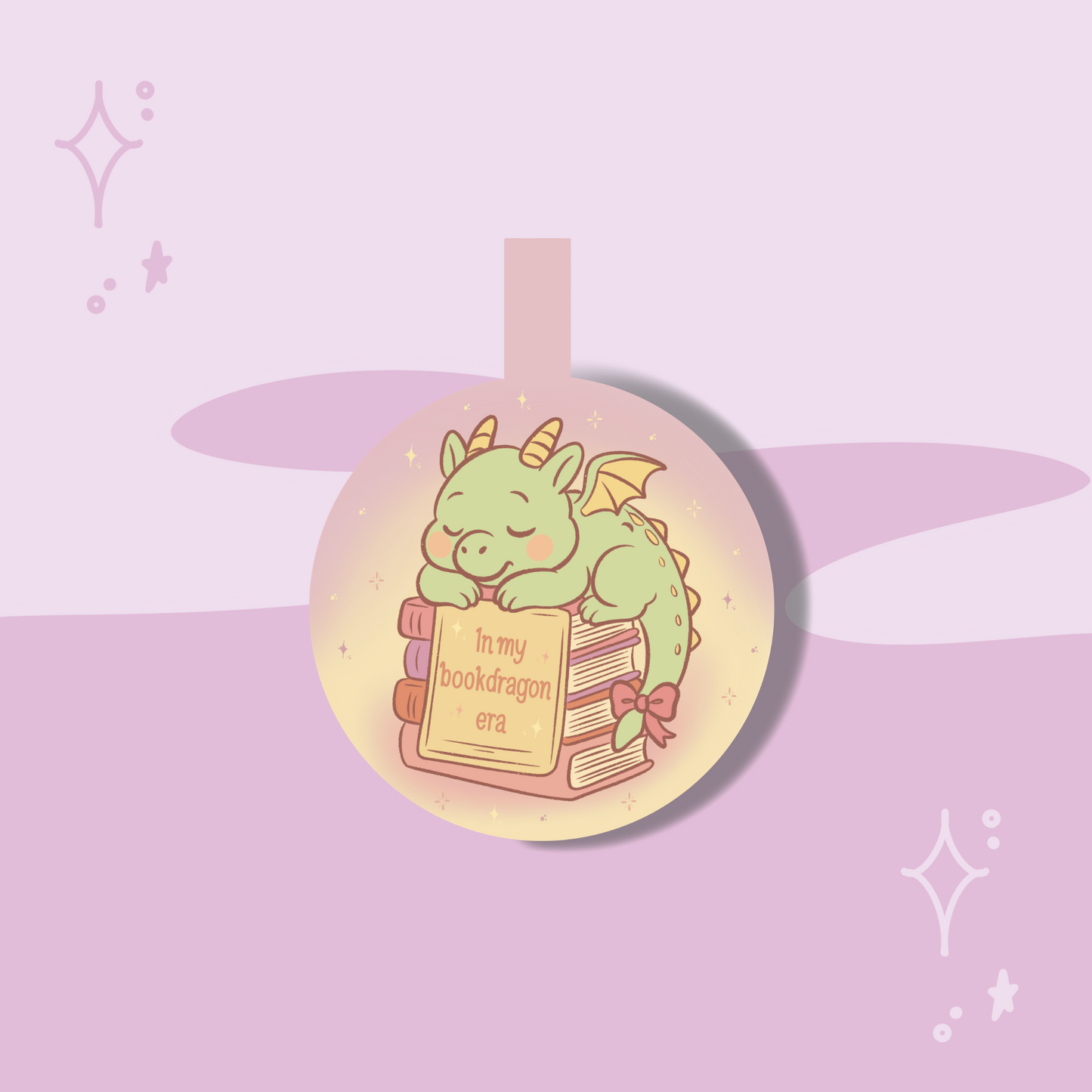 Circular pendant with a green dragon illustration and text on a pink and purple gradient background